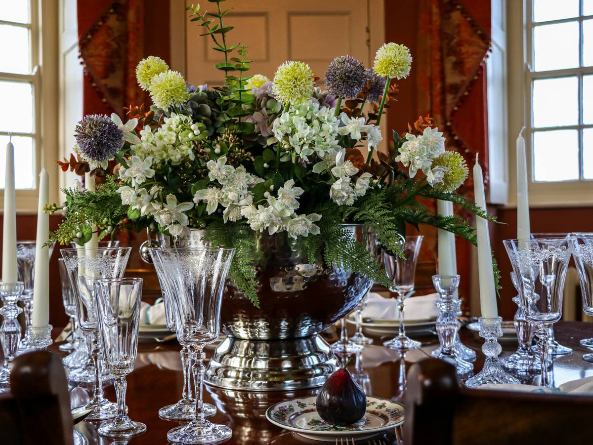 table centerpieces ideas for home featuring low floral arrangement with seasonal fruit and neutral candles on a wooden dining table